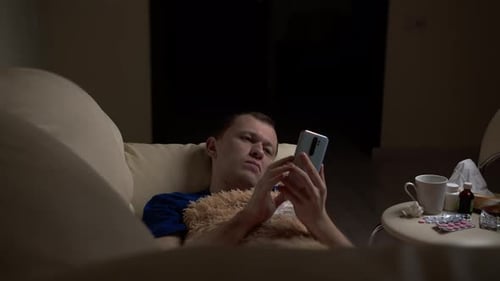 Man Resting on Couch While Using Phone