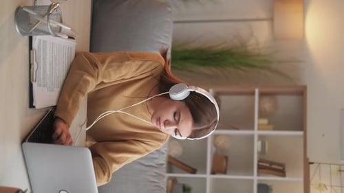 Woman Working on Laptop at Desk with Headphones