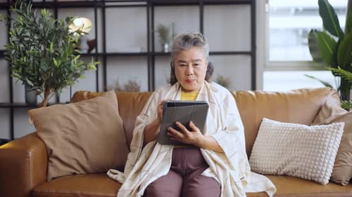 Senior Woman Using Tablet on Couch at Home