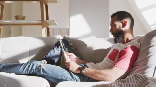 Young Man Relaxes on Couch with Tablet