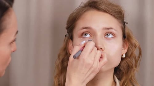 Applying Makeup to Young Woman's Face Close Up