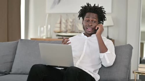 Young Adult Sits on Couch Using Laptop