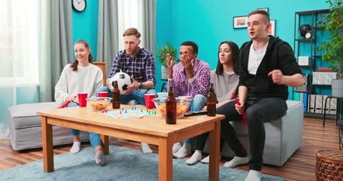 Upset Friends Watching Football and Drinking at Home Sitting on a Couch