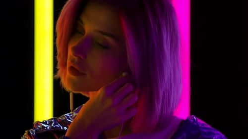Portrait of a Young Stylish Woman Looking at the Camera Wears White Headphones and Listens To Music