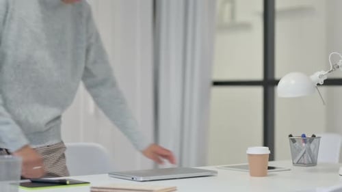 Young Adult Opens Laptop in Bright Office Setting