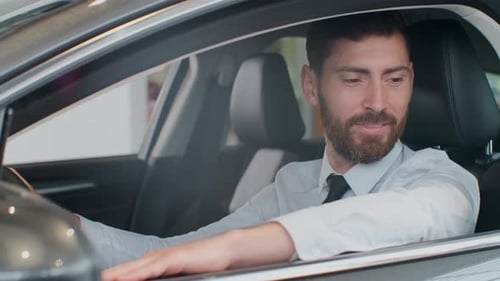 Smiling Man Sitting Inside New Car at Dealership