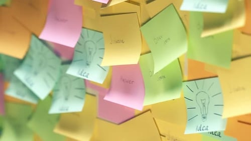 The collage of multiple colorful post-it notes on the wall with idea text.