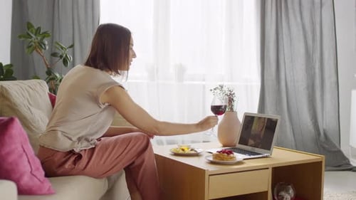 Woman Chatting with Friend on Laptop Drinking Wine