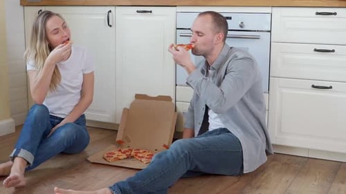 Young Couple Eating Pizza in Kitchen Together