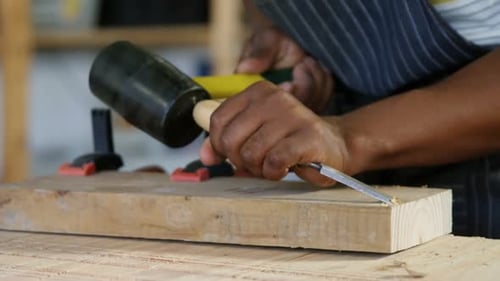 Mid section of carpenter carving wood with hammer at table 4k