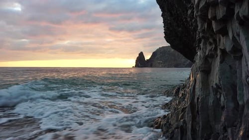 Colorful Warm Sunset Over the Sea and Volcanic Basalt Rocks Like in Iceland