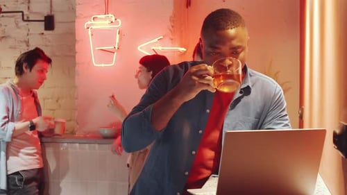 Homme noir buvant du thé et utilisant un ordinateur portable dans un espace de coworking