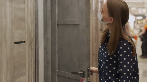 Woman Wearing a Protective Mask in a Store Buys a Wooden Door for a New House