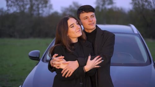 Loving Couple Embraces Near Car at Sunset