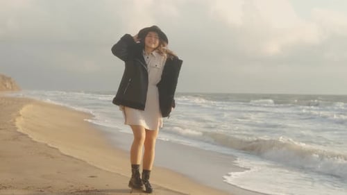 Portrait of Romantic Brunette Woman in Hat and Leather Jacket Walking on the Beach in Autumn at