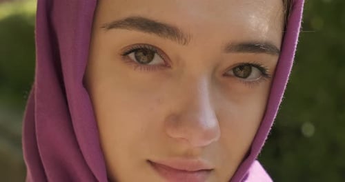 Schöne junge Frau blickt in die Kamera und trägt ein traditionelles Kopftuch. Attraktive Frau im Hijab