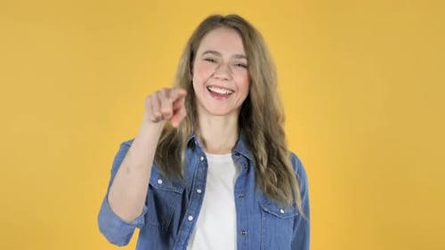 Smiling Woman Points Forward on Yellow Background