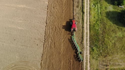 Tractor with a Long, Tiered Plow Plows the Field, Preparing Virgin Land in the Spring