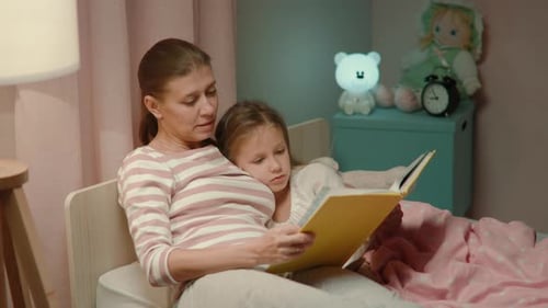 Mother Reads Bedtime Story to Daughter at Night