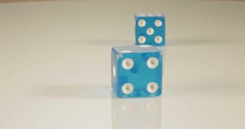 Macro disparo a cámara lenta de dados cayendo y rodando sobre una superficie reflectante