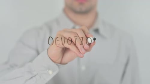 Young Adult Writes the Word Devotion on Surface