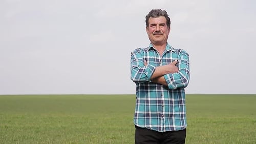 A Front View of a Portrait Happy Owner Farmer Man with His Hands Crossed in Field