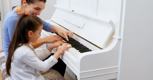 Woman and Girl Play White Piano Together
