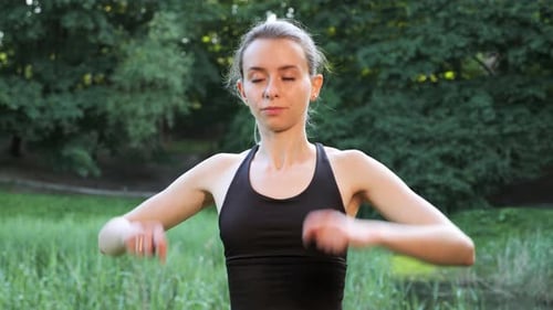 Young Blond Sportswoman Stretching Arms Before Exercising in Summer Park Outdoor