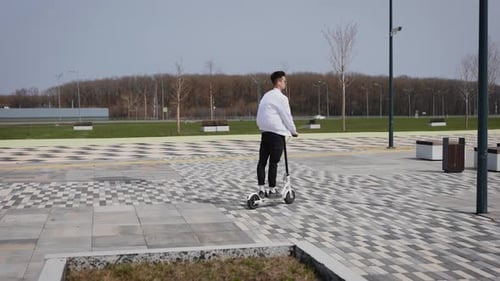 Ein attraktiver junger Mann fährt einen Elektroroller