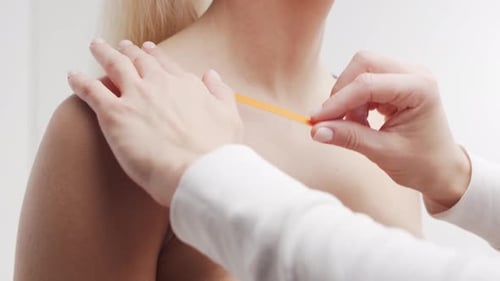 El terapeuta está aplicando cinta kinesiológica en la cara femenina. Tratamiento de kinesiología y recuperación.