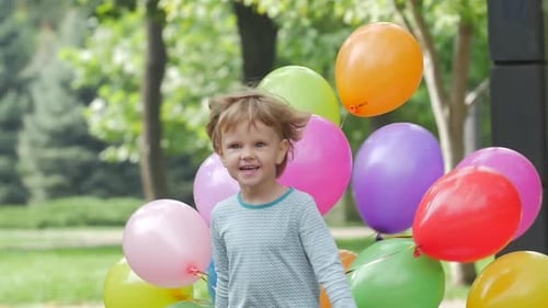 Happy Child Running with Colorful Balloons in Park