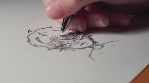 Close-up girls arm drawing a boy on a white paper by pen