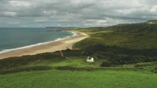 Ocean Bay Sandy Beach Aerial Panoramic View Under Gray Thick Clouds. Green Meadows in Irish Valleys