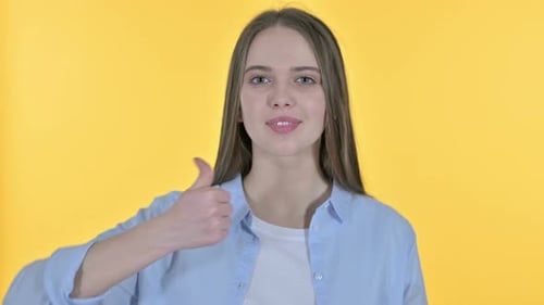 Happy Woman Gives Thumbs Up on Yellow Background