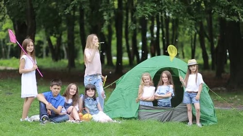 Smiling Children Gathered Around Green Tent Outdoors