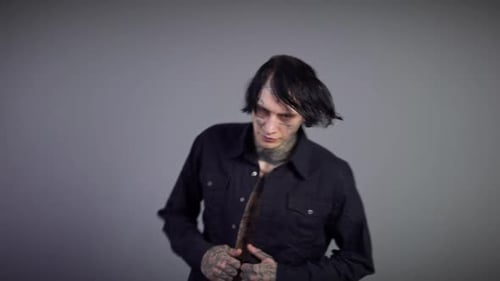 Young Adult with Tattoos Opens Shirt