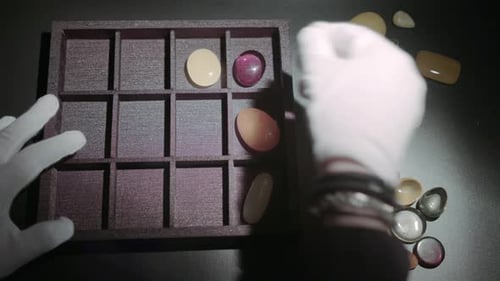 Hands Organising Polished Gemstones into Storage Box