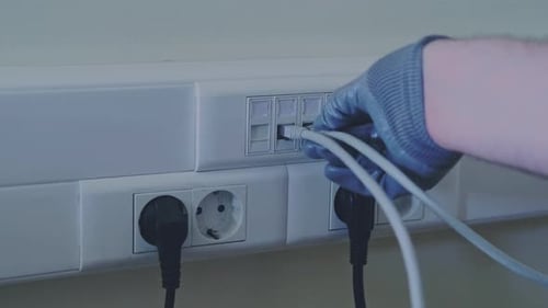 Connection to a computer network in the office, a gloved hand holds a cord