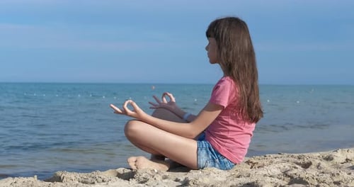 Teen Meditating on Beach in Lotus Position