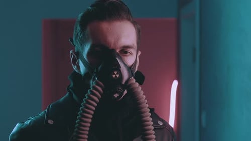Brutaler Mann mit Atemschutzmaske blickt nachts über Neonlichtern im Cyberpunk-Stil in die Kamera