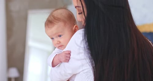 Young Mother Holds Her Baby Daughter in Her Arms and Looks Affectionately Kisses Her Tenderly