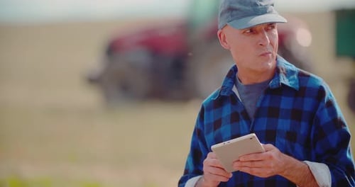 Farmer Using Digital Tablet While Examining Field