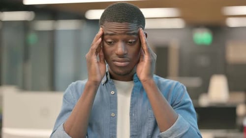 Stressed Young Man Rubbing Temples in Office