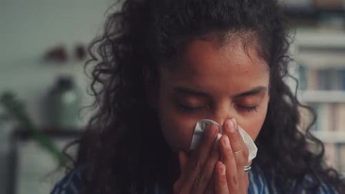 Allergic Indian Woman Blowing Nose in Tissue Sit on Sofa at Home Office