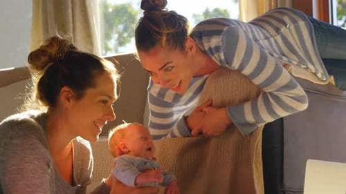 Women Admire Adorable Infant in Bright Home