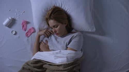 Woman Sleeping Restlessly in Bed With Pills