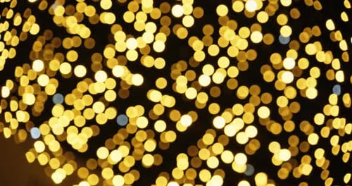 Defocussed Shot Of Twinkling Golden Christmas Lights Against Night Sky