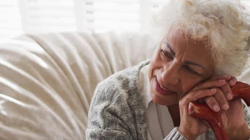 Smiling Senior Woman Resting with Cane Indoors