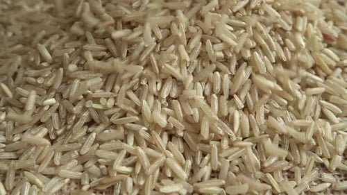 Brown Rice Grains Falling on Burlap Background