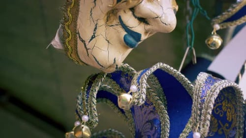 Close up tilting down shot of several elegant carnival masks blowing in the breeze.